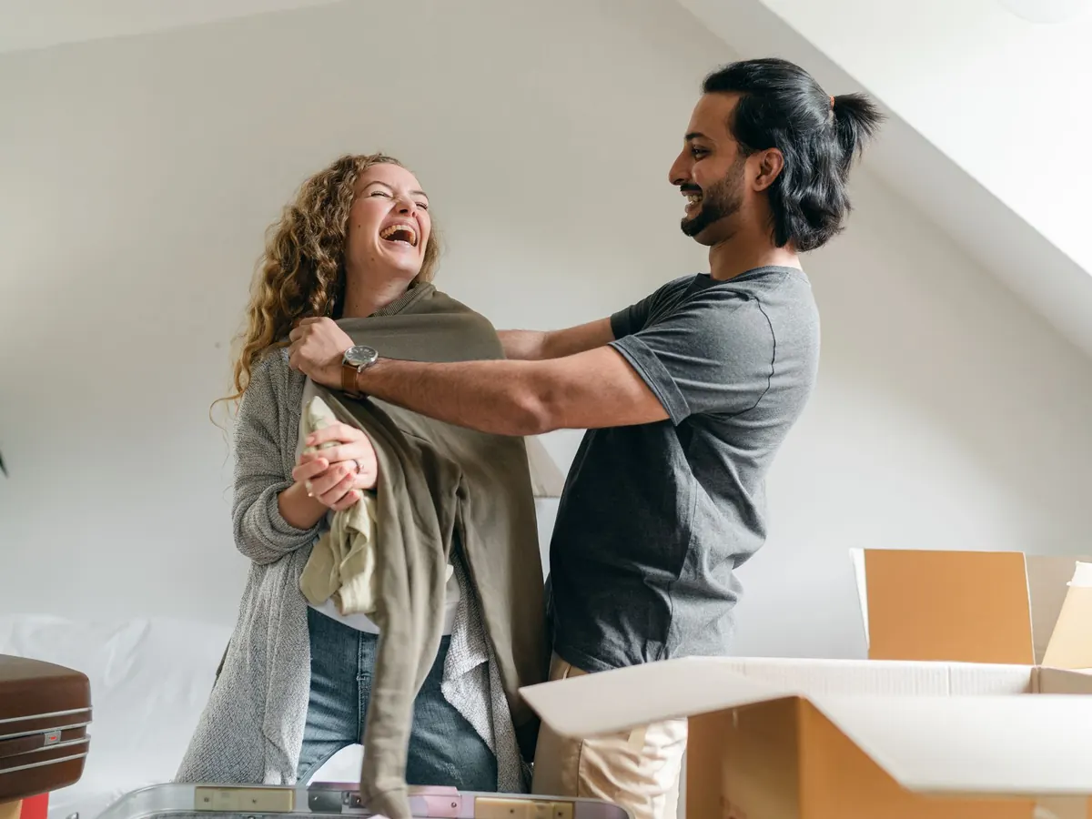 A couple laughing while unpacking boxes in a new home