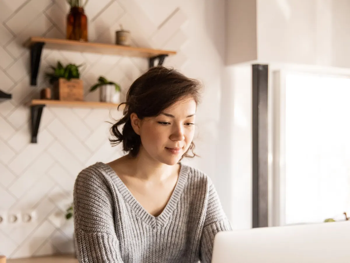 A person working on a laptop at a kitchen counter