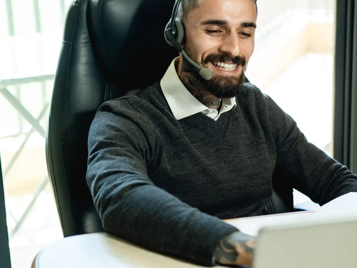 A smiling specialist with a headset at a laptop